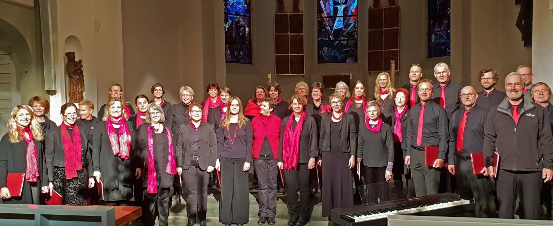 40 Sängerinnen und Sänger der Oldesloer Singakademie in schwarz-rot beim Weihnachtskonzert in der Kirche